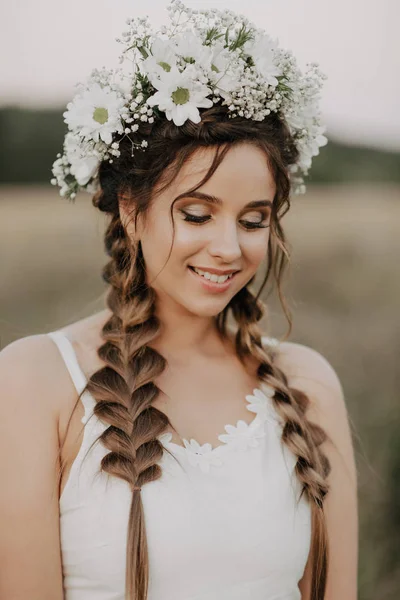 Gelukkig lachend meisje met vlechten en bloemen krans in witte jurk in boho stijl in de zomer buiten — Stockfoto