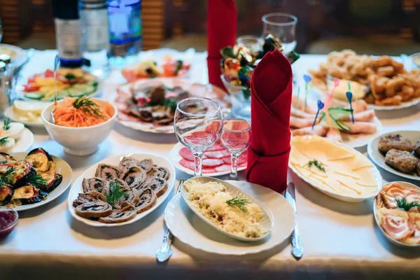 Праздничный стол в ресторане с тарелками, стаканами и столовыми приборами на белой скатерти — стоковое фото