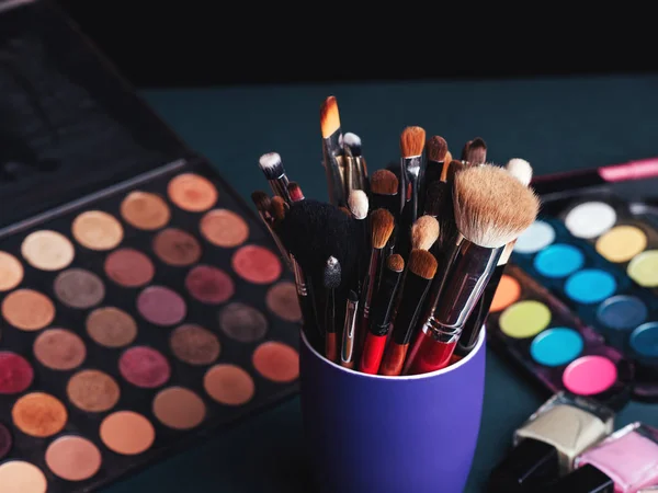 Conjunto de escovas de maquiagem profissional no fundo de uma paleta com sombras coloridas e cosméticos — Fotografia de Stock