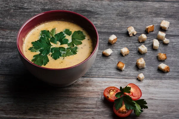 Kürbiscremesuppe in einem Teller auf einem Holztisch — Stockfoto