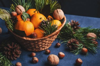 Çam kozalakları ve dallarla süslenmiş mandalina, ceviz ve fındık.