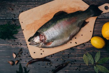 Mutfakta rustik tarzda ahşap bir masada bir tahta üzerinde çiğ alabalıklar