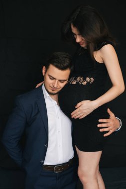 Mutlu ebeveynler bebek bekliyor. Bir adam hamile bir kadına karnından sarılır.
