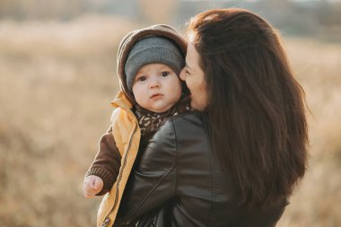 Genç anne küçük oğlunu kollarında tutuyor.