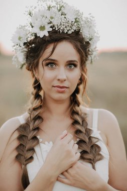 örgüler ve çiçek çelenk yaz açık havada beyaz boho elbiseli bir kız portresi