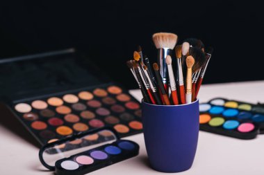 Göz farı paletinin arka planında makyaj fırçası seti