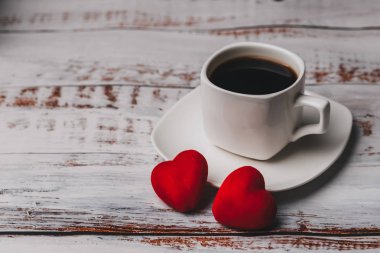 Bir fincan kahve ve birkaç kırmızı kalp. Sevgililer Günü için tebrik kartı