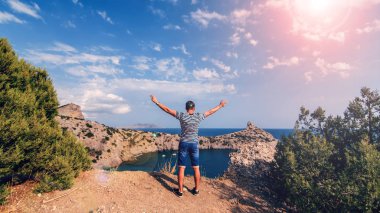 deniz ve yaz aylarında güneşli gökyüzü karşı elleri ile dağların üstüne adam gezgin geri