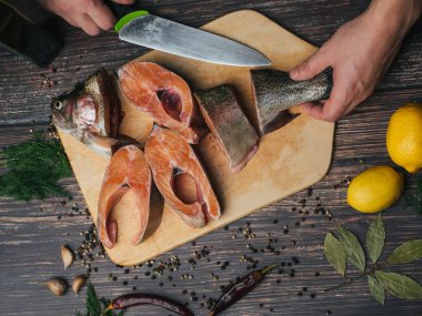 adam aşçı alabalık elinde bir bıçak kesiyor. Taze çiğ kesik kırmızı balık