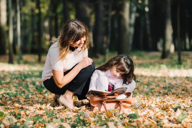 Anne ve kızı parkta içinde sonbahar çizmek ve mutlu