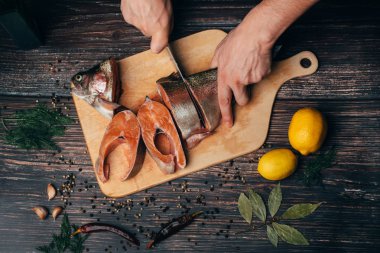 adam bir bıçak taze çiğ alabalık yemek pişirmek için parçalar halinde keser