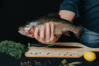 Alabalık mutfak arka plan üzerinde bir adamın elinde. Şef ile büyük taze balık