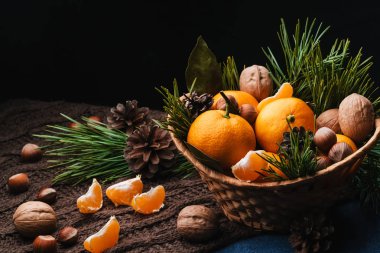 Çam kozalakları ve dallarla süslenmiş mandalina, ceviz ve fındık.