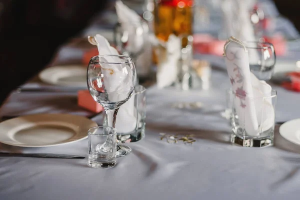 Ensemble de verres vides et assiettes avec couverts sur une nappe blanche sur la table dans le restaurant — Photo