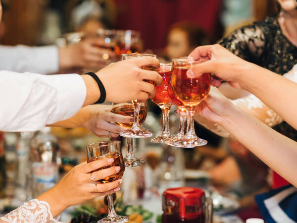 hands of a group of people clinking and toasting glasses of red wine at a festive party in a restaurant