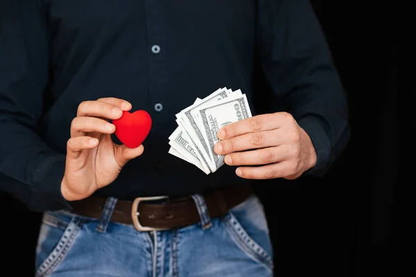 Banknotes of money and a red heart in the hands of a man — Stock Photo, Image
