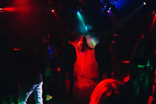 Silhouetten von Menschen, die bei einer Party in einem Nachtclub auf der Tanzfläche tanzen — Stockfoto