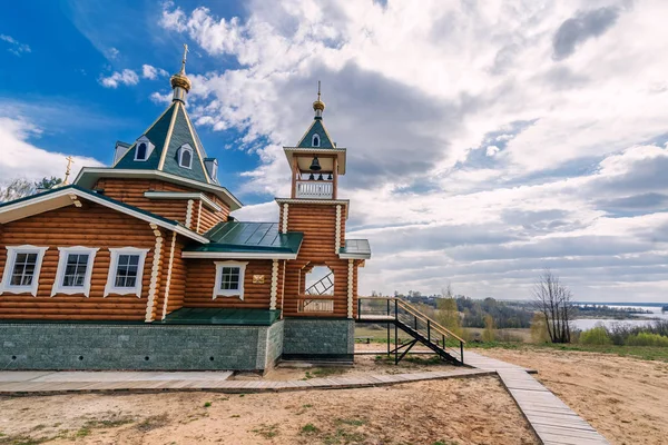 夏にロシアの川岸に正統派キリスト教の近代的な木製の教会 — ストック写真