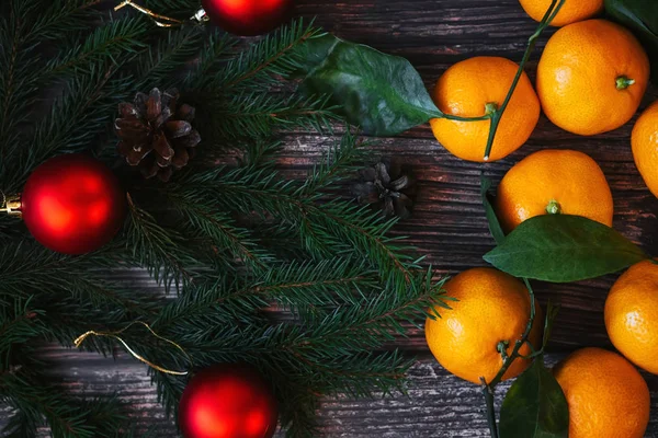 木製のテーブルの上にマンダリン、モミの枝、赤いボールと松のコーンとクリスマスの背景。伝統的なお祝いの冬の装飾 — ストック写真