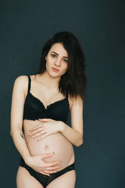 Embarazada joven caucásico morena chica posando en negro ropa interior —  Fotos de Stock