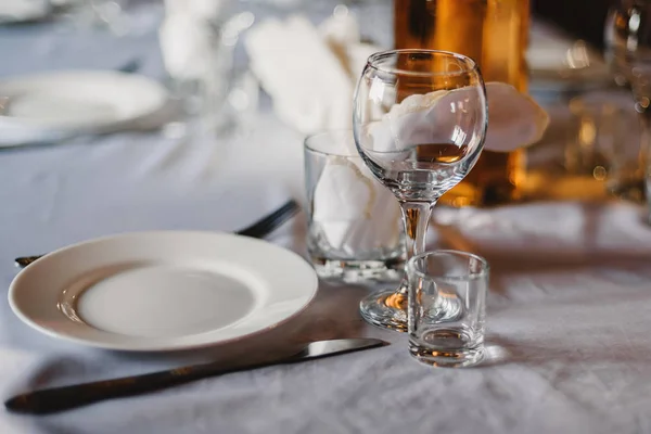 Set of empty glasses and plates with Cutlery on a white tablecloth on the table in the restaurant — Stock Photo, Image
