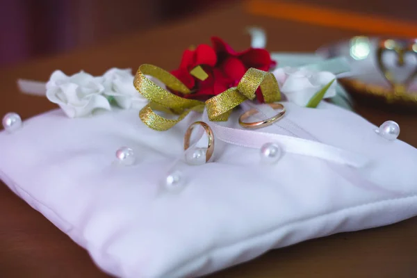 Dos anillos tradicionales de boda de oro en un cojín blanco — Foto de Stock