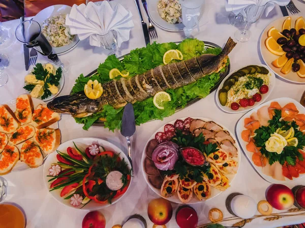 Традиционная русская кухня с запеченной фаршированной щукой и другими закусками на праздничном столе в ресторане — стоковое фото