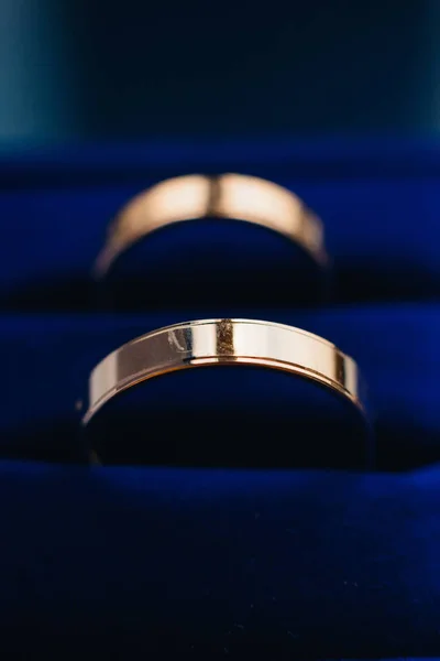 Pár arany jegygyűrű fekszik egy kék doboz — Stock Fotó