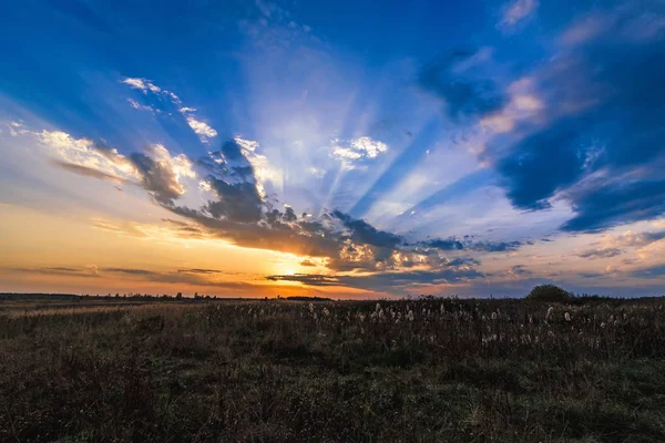 Belo pôr do sol colorido com raios laranja do sol no céu azul à noite no outono — Fotografia de Stock