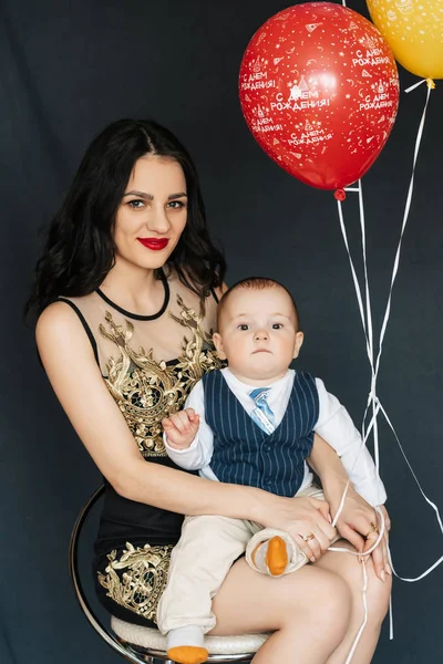 Giovane mamma ragazza con ragazzo bambino figlio tra le braccia con palloncini per il compleanno — Foto Stock