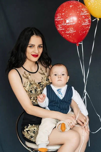 Jeune maman fille avec garçon bébé fils dans ses bras avec des ballons pour l'anniversaire — Photo