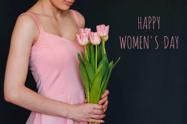 Ramo de flores de tulipanes rosados en las manos de una niña. Tarjeta de felicitación con texto Feliz Día de la Mujer — Foto de Stock