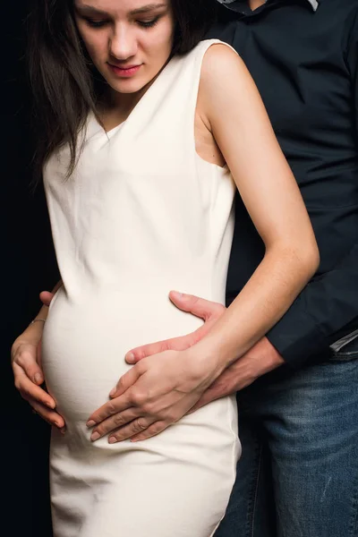 Uomo abbraccia la pancia di una ragazza incinta. La coppia aspetta un bambino — Foto Stock
