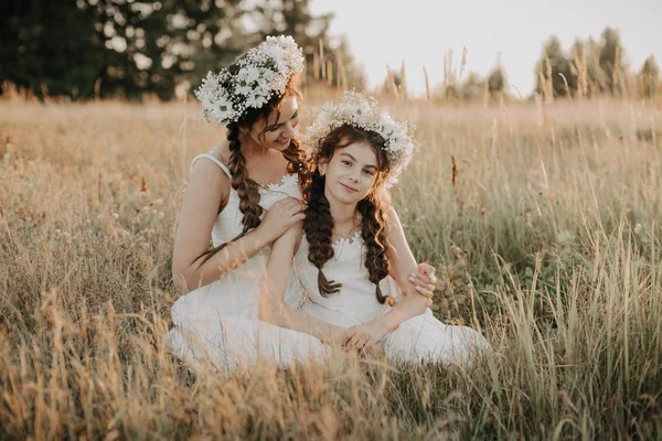 Gelukkig moeder en dochter glimlachend en knuffelen op het gras in het veld in de zomer — Stockfoto