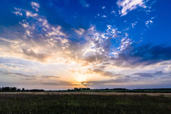 Paisaje con amanecer y sol en un cielo azul nublado sobre el campo en verano —  Fotos de Stock