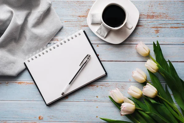Boş bir defter, bir fincan kahve ahşap zemin ile Beyaz Lale buketi