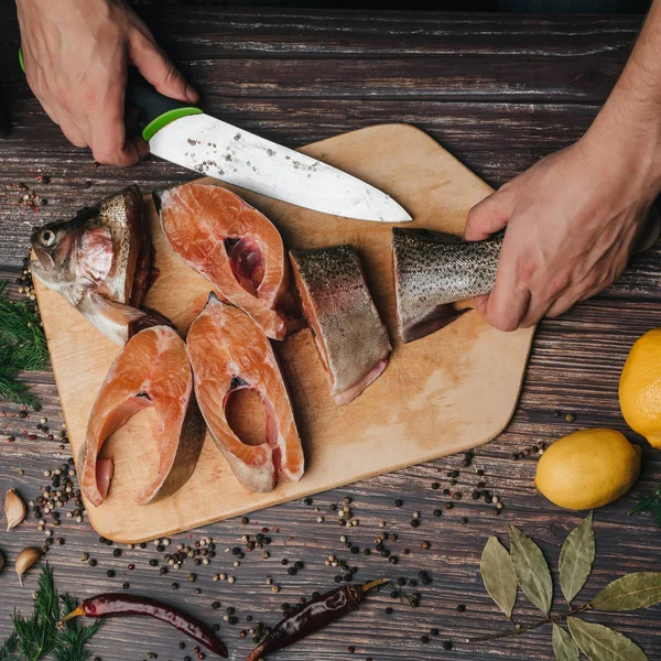 Hombre cortes cuchillo rojo pescado en madera Junta — Foto de Stock