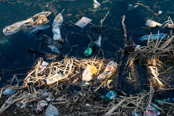 VICHUGA, RUSSIE - 21 AVRIL 2019 : Diverses ordures et déchets provenant de bouteilles et sacs en plastique dans l'eau et sur la rive de la rivière — Photo