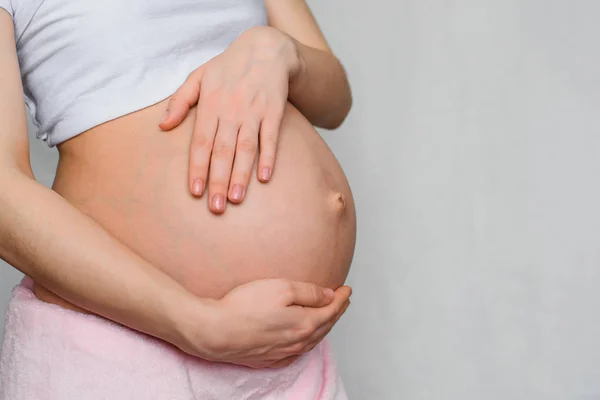 Schwangere Mädchen umarmt ihren Bauch mit ihren Händen — Stockfoto