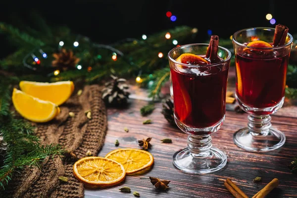 Δύο ποτήρια χριστουγεννιάτικο ζεστό κρασί με μπαχαρικά και φέτες πορτοκαλιού σε ένα ξύλινο τραπέζι ρουστίκ — Φωτογραφία Αρχείου