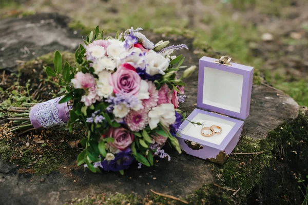 Anillos de boda en una caja junto al ramo — Foto de Stock