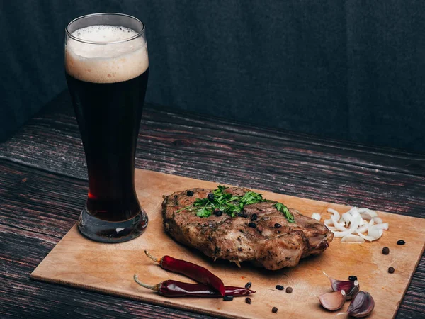 Varkensvlees met knoflook, peper, ui en een glas donker bier — Stockfoto