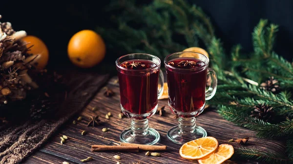 Baharatlar ve portakal dilimleri ahşap bir masa üzerinde mulled şarap iki kadeh. Sıcak alkollü içecek — Stok fotoğraf