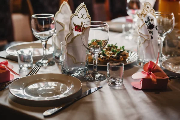 Juego de vasos y platos vacíos con cubiertos sobre un mantel blanco sobre la mesa en el restaurante —  Fotos de Stock