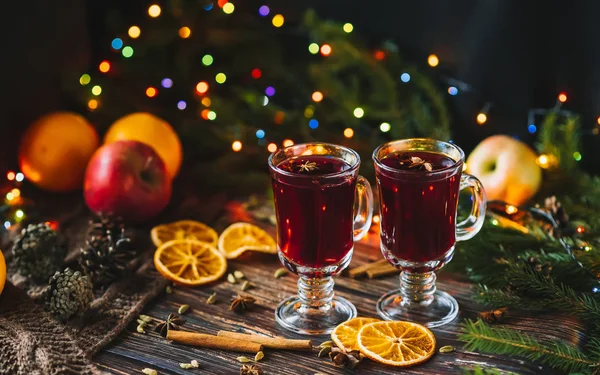 Vino caliente en copas de cristal con rodajas de naranja, manzanas y especias con decoración navideña — Foto de Stock