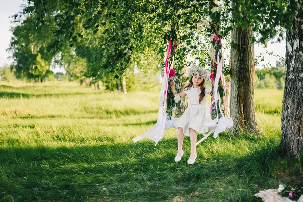 A swing lány szalagokkal díszített, és virágok, a természet egy napsütéses nyári napon — Stock Fotó