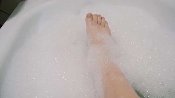 Schöne brünette Mädchen streichelt sexuell ihr Bein und singt im Badezimmer mit Schaum — Stockvideo