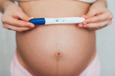 hamile bir genç kızın elinde pozitif gebelik testi