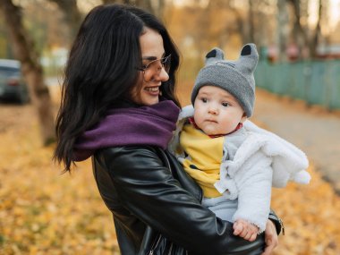 Genç, güzel, beyaz bir kız annesi gülümsüyor ve küçük oğlunu kucağına alıyor.