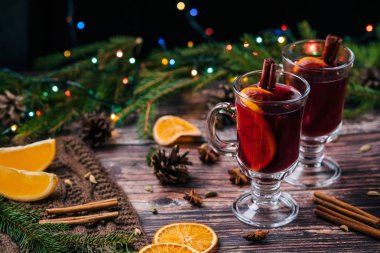 Tarçın, Yıldız anason, kakule, karanfil ve portakal dilimleri ahşap bir masa ile iki bardaklarda mulled şarap